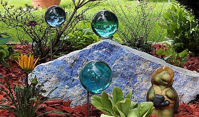 Verschiedene Glaskugeln im Garten mit Glaskugelhalter